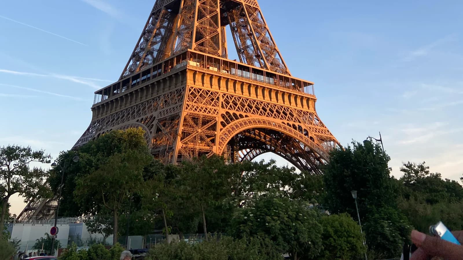 The Eiffel Tower lit gold at sunset above the Paris treeline