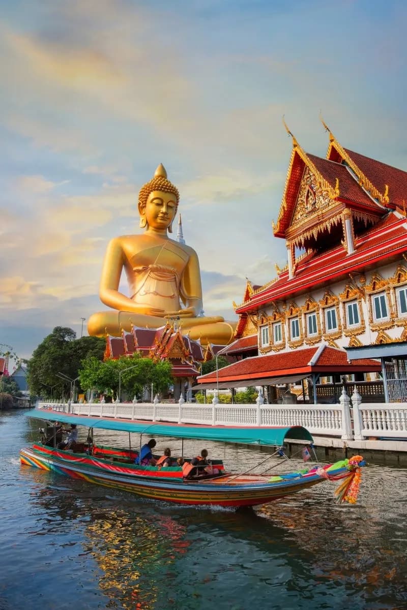 A golden Buddha statue beside a riverside temple in Bangkok